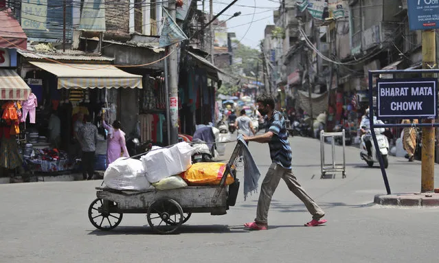 A laborer pushes a goods-filled cart at a market in Jammu, India, Friday, June 19, 2020. (Photo by Channi Anand/AP Photo)