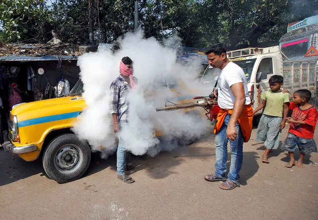 A taxi driver covers his face as a municipal worker fumigates a market to prevent the spread of dengue fever and other mosquito-borne diseases in Kolkata, India, November 20, 2017. (Photo by Rupak De Chowdhuri/Reuters)