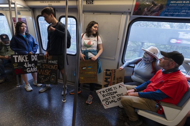 Metro train riders carry signs before attending a rally to protest President Donald Trump and Elon Musk, Saturday, April 5, 2025, in Washington. (Photo by Manuel Balce Ceneta/AP Photo)