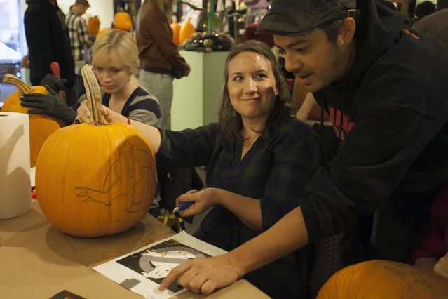 Chris Soria of the Maniac Pumpkin Carvers gives an attendee some tips on tackling a Ghostbuster design on a pumpkin at Cotton Candy Machine in Brooklyn, N.Y. on October 18, 2014. (Photo by Siemond Chan/Yahoo Finance) 