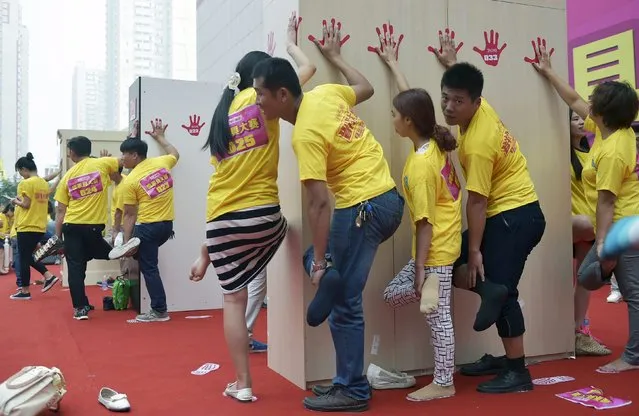 Contestants participate in an endurance competition by putting one hand on a piece of furniture while standing on one leg, at a furniture department store in Luoyang, Henan province, China, September 19, 2015. The last 10 people who held on for over three hours were each rewarded a piece of furniture, local media reported. (Photo by Reuters/China Daily)