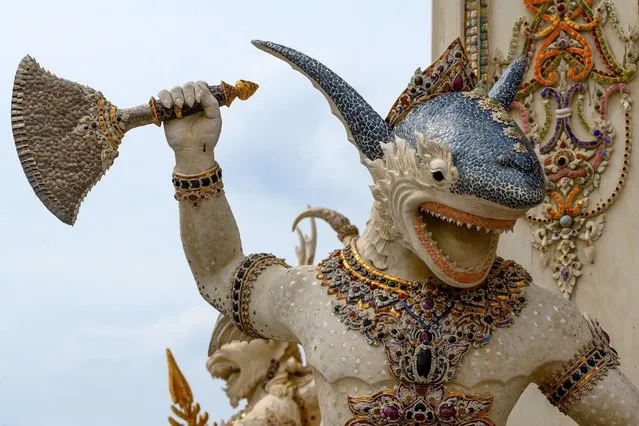 This photograph taken on July 14, 2020 shows a shark-man statue with an axe decorating the outside of the Wat Pariwat Buddhist temple in Bangkok. Wat Pariwat, also known as “the David Beckham Temple”, is decorated with statues of superheroes and comic characters as well as mythical and imaginary creatures. A golden-plated sculpture of the English football player holding the base of a Buddha statue in one of the buildings gives the temple its nickname. (Photo by Mladen Antonov/AFP Photo)