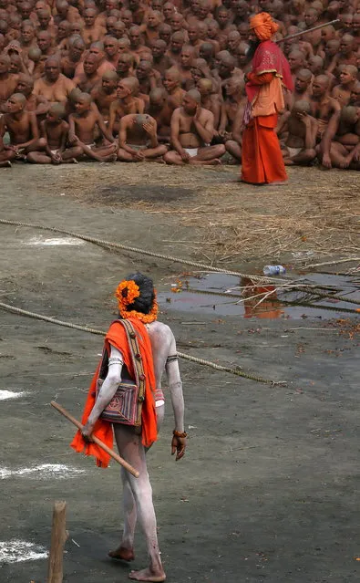 A Naga Sadhu, foreground, walks past Hindu holy men of the Juna Akhara sect participate in rituals that are believed to rid them of all ties in this life and dedicate themselves to serving God as a “Naga” or naked holy men, at Sangam, the confluence of the Ganges and Yamuna River during the Maha Kumbh festival in Allahabad, India, Wednesday, February 6, 2013. The significance of nakedness is that they will not have any worldly ties to material belongings, even something as simple as clothes. This ritual that transforms selected holy men to Naga can only be done at the Kumbh festival.(Photo by Manish Swarup/AP Photo)