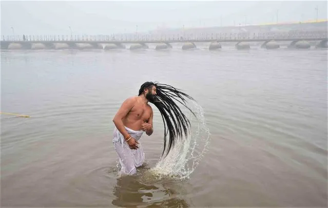 A Sadhu, or Hindu holy man, takes a ritualistic dip at the Sangam, the meeting point of the Ganges and the Yamuna rivers, on Paush Purnima day during the annual traditional Magh Mela fair in Prayagraj, in the northern Indian state of Uttar Pradesh, Friday, January 6, 2023. Hundreds of thousands of devout Hindus are expected to take holy dips at the confluence during the astronomically auspicious period of over 45 days celebrated as Magh Mela. (Photo by Rajesh Kumar Singh/AP Photo)