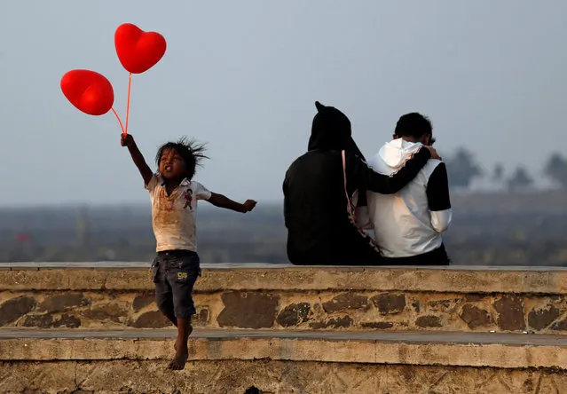 A child jumps from a promenade after attempting to sell heart-shaped balloons to a couple on Valentine's Day in Mumbai, India February 14, 2018. (Photo by Francis Mascarenhas/Reuters)