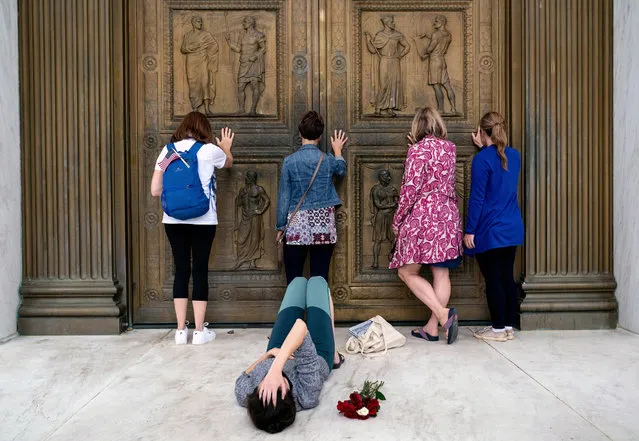 Conservative women who support Judge Amy Coney Barrett's nomination to the Supreme Court, pray while touching the doors of the Supreme Court in Washington as Jacquelyn Booth lays on the ground mourning the death of Justice Ruth Bader Ginsburg on Saturday, September 26, 2020. Barrett is a new kind of icon for some, one they have not seen before in American cultural and political life. (Photo by Erin Schaff/The New York Times)