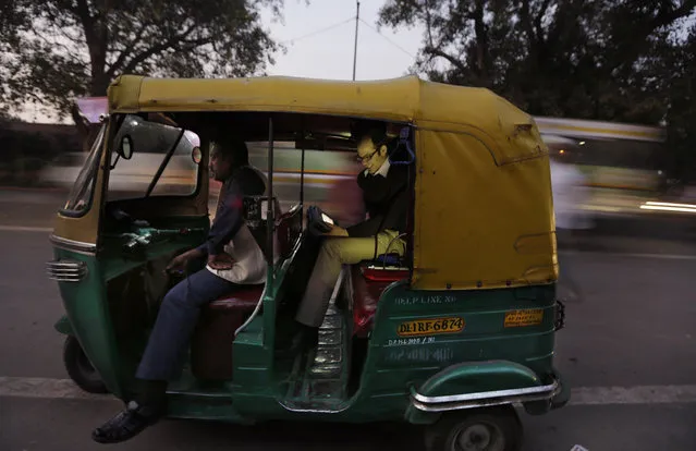 In this Tuesday, November 25, 2014 photo, U.S. scientist Joshua Apte monitors pollution levels on his laptop as he travels in an open-aired auto-rickshaw during rush-hour traffic in New Delhi, India. Apte has alarming findings for anyone who spends time on or near the roads in this city of 25 million, with numbers far worse than the ones that have already led the World Health Organization to rank New Delhi as the world's most polluted city. (Photo by Altaf Qadri/AP Photo)