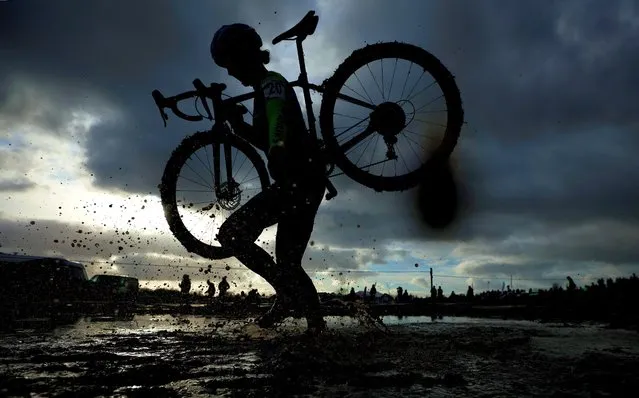 A competitor carries her bike during the Senior Women's race at the British Cyclocross championships near Milnthorpe, Britain on January 15, 2023. (Photo by Phil Noble/Reuters)