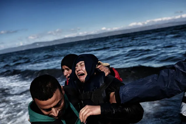 A man comforts a woman upon arrival with other refugees and migrants on the Greek island of Lesbos on October 25, 2015 after they crossed the Aegean sea from Turkey.  At least three migrants – two children and a woman – drowned when their boat sank off the Greek island of Lesbos, the coastguard said, the latest fatalities in Europe's refugee crisis. (Photo by Aris Messinis/AFP Photo)