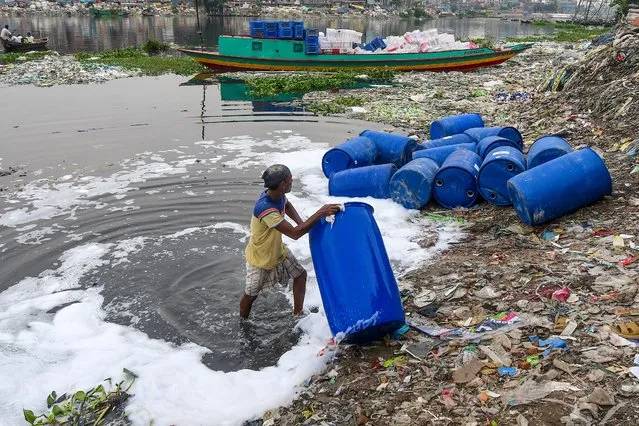 A worker cleans barrels used to contain chemicals in Buriganga river in Dhaka on September 27, 2020. (Photo by Munir Uz Zaman/AFP Photo)