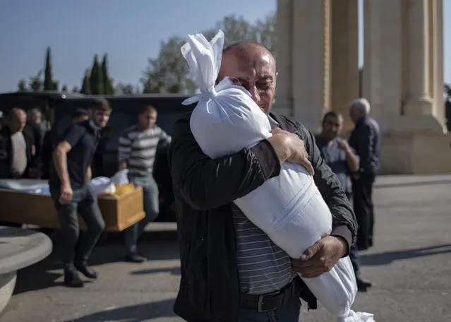 Timur Haligov, an Azerbaijani Turkish father embraces the body of his 10-month-old baby girl, Narin, who was killed by overnight shelling by Armenian forces. during a funeral ceremony, in Ganja, Azerbaijan, Saturday, October 17, 2020. Azerbaijan has accused Armenia of striking its second-largest city with a ballistic missile that killed at least 13 civilians and wounded 50 others in a new escalation of their conflict over Nagorno-Karabakh. (Photo by Can Erok/DHA via AP Photo)