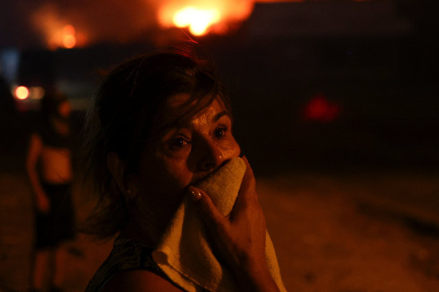 A woman covers her mouth, while locals evacuate, as wildfire continues to burn, in Delvina, Albania on August 12, 2025. (Photo by Florion Goga/Reuters)