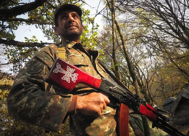 A volunteer soldier armed with a machine gun poses for a photo near a front line at a military base during a military conflict in the separatist region of Nagorno-Karabakh, Tuesday, October 27, 2020. Fighting over Nagorno-Karabakh is raging, unimpeded by a U.S.-brokered cease-fire, while Armenia and Azerbaijan are trading blame for the deal's quick unraveling. (Photo by AP Photo/Stringer)
