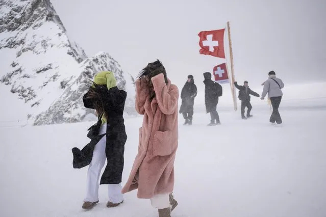 Tourists take shelter from the wind during their trip at the Jungfraujoch, 3500 meters high in the Swiss Alps, above the village of Wengen on January 12, 2023. (Photo by Marco Bertorello/AFP Photo)