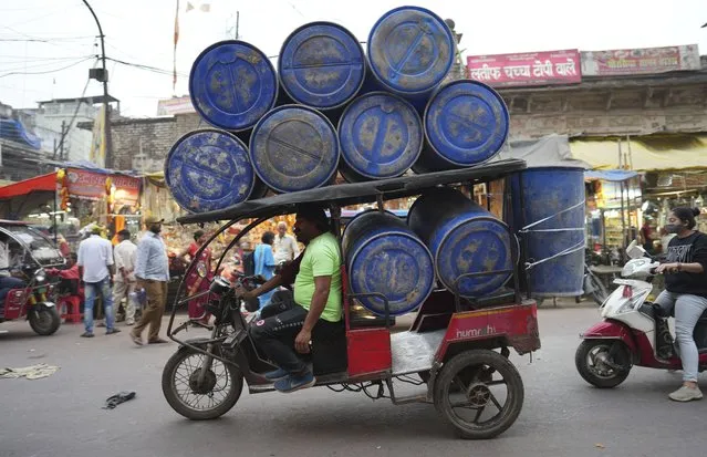 An electric rickshaw carries barrels in Prayagraj, in the northern Indian state of Uttar Pradesh, Thursday, March 16, 2023. (Photo by Rajesh Kumar Singh/AP Photo)