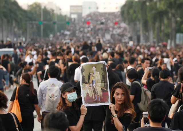 Mourners hold up a picture of Thailand's late King Bhumibol Adulyadej as they leave the Grand Palace in Bangkok, Thailand, October 14, 2016. (Photo by Edgar Su/Reuters)
