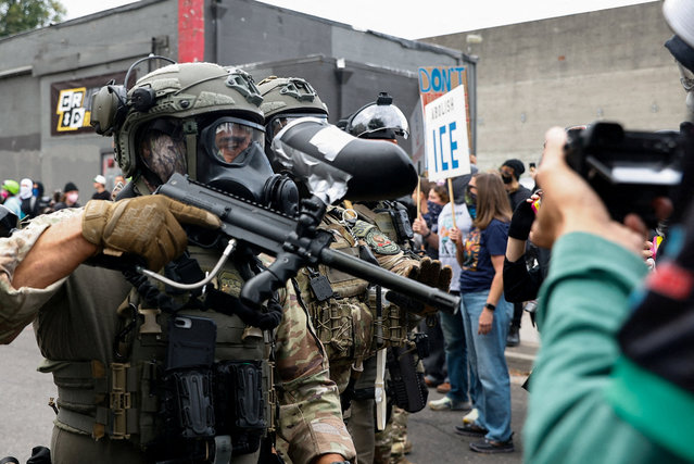 A law enforcement officer holds a gun in front of the ICE headquarters in Portland, Oregon, U.S., October 4, 2025. (Photo by John Rudoff/Reuters)