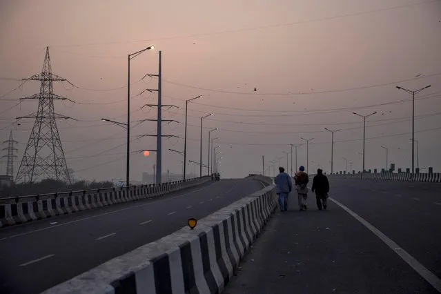 Farmers walk on an empty blocked highway as they attend a protest against the newly passed farm bills at the Delhi-Uttar Pradesh border in Ghaziabad, India, December 7, 2020. (Photo by Danish Siddiqui/Reuters)