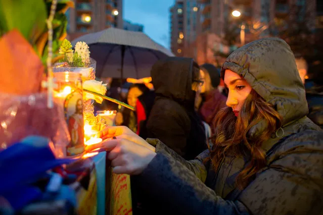 A woman lights a candle during a vigil April 24, 2018 in Toronto, Canada, near the site of the previous day' s deadly street van attack. A van driver who ran over 10 people when he plowed onto a busy Toronto sidewalk was charged with murder Tuesday, as Canadian Prime Minister Justin Trudeau urged a rattled nation not to live in fear after the “senseless attack”. Police said the suspect, 25- year- old Alek Minassian, was not known to them before Monday's carnage in Canada's most populous city, which also left 15 people injured. (Photo by Geoff Robins/AFP Photo)