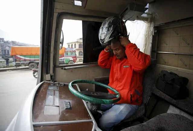 Jetha Lama, a driver of a long distance passenger bus, wears his helmet before driving his vehicle that arrived from Kankadvitta near the India-Nepal border, during the ongoing fuel crisis that has been continuing for over a month now, in Kathmandu, Nepal October 30, 2015. (Photo by Navesh Chitrakar/Reuters)