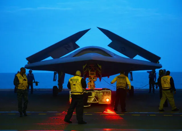 An X-47B Unmanned Combat Air System (UCAS) demonstrator is towed into the hangar bay of the aircraft carrier USS George H.W. Bush (CVN 77). George H.W. Bush is scheduled to be the first aircraft carrier to catapult-launch an unmanned aircraft from its flight deck. (Photo by Mass Communication Specialist 2nd Class Timothy Walter/U.S. Navy Photo)