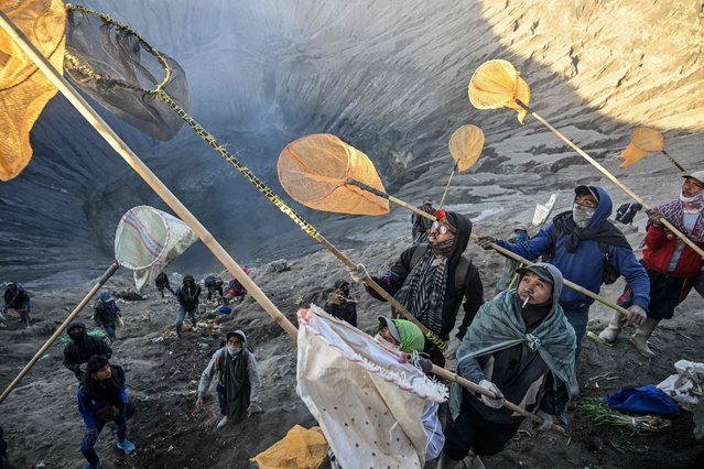 Villagers use nets to catch offerings thrown by members of the Tengger sub-ethnic group in the crater of the active Mount Bromo volcano as part of the Yadnya Kasada festival in Probolinggo, East Java province on June 22, 2024. (Photo by Juni Kriswanto/AFP Photo)