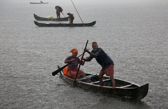 A fisherman and his wife row their boat in a fishing farm as it rains heavily on the outskirts of Kochi, India, May 29, 2018. (Photo by Sivaram V/Reuters)