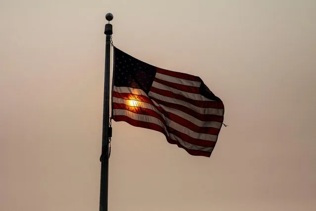 An American flag flutters in front of the sun shrouded in haze and smoke caused by wildfires in Canada, in Washington, U.S., June 8, 2023. (Photo by Amanda Andrade-Rhoades/Reuters)