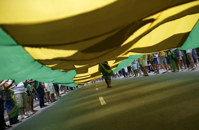 A demonstrator carries a Brazilian national flag during a protest calling for the impeachment of Brazil's President Dilma Rousseff in Rio de Janeiro, Brazil, December 13, 2015. (Photo by Ricardo Moraes/Reuters)