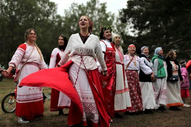 Women wearing traditional Russian village-style clothes dance while celebrating the summer solstice near a bonfire in the village of Okunevo, about 200 kilometers (about 125 miles) northeast of the Siberian city of Omsk, Russia, on Wednesday, June 21, 2023. (Photo by Evgeniy Sofiychuk/AP Photo)