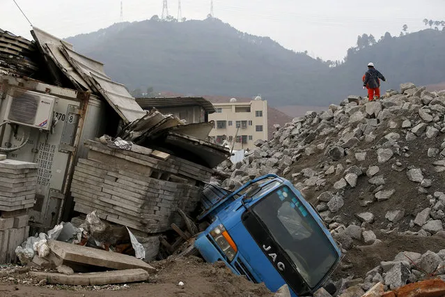Rescue workers walk past a damaged vehicle in the industrial park hit by a landslide in Shenzhen, Guangdong province, December 22, 2015. (Photo by Kim Kyung-Hoon/Reuters)