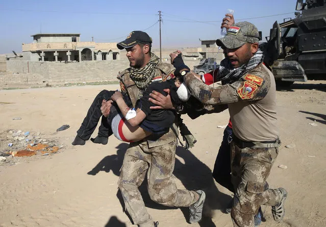 An Iraqi special forces soldier from the medical unit carries an injured boy who was wounded by a mortar shell at al-Tahrir neighborhood, on a field hospital at al-Samah front line neighborhood, in Mosul city, Iraq, Wednesday, November 23, 2016. (Photo by Hussein Malla/AP Photo)