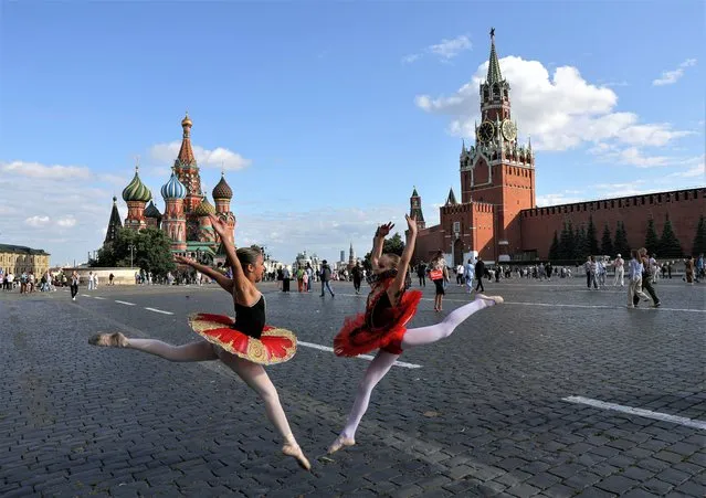 Girls in ballet dresses pose near St. Basil's Cathedral and the Kremlin's Spasskaya Tower in Red Square in central Moscow, Russia on July 19, 2023. (Photo by Evgenia Novozhenina/Reuters)