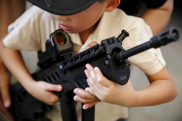 A boy carries a weapon during the Children's Day celebration at a military facility in Bangkok, Thailand January 9, 2016. Army barracks opened their doors to children to interact with their weapons and vehicles as part of the celebration. (Photo by Jorge Silva/Reuters)