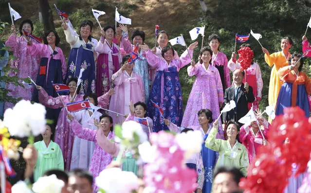 Women wearing traditional dress line the streets of Pyongyang, North Korea, to welcome South Korean President Moon Jae-in and North Korean leader Kim Jong Un passing by during a car parade, Tuesday, Sept. 18, 2018. (Pyongyang Press Corps Pool via AP)