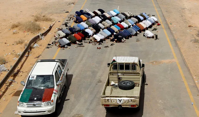 Anti-Gaddafi fighters pray at a checkpoint near the town of Abu Grein, west of Sirte, one of Muammar Gaddafi's last remaining strongholds September 12, 2011. (Photo by Goran Tomasevic/Reuters)