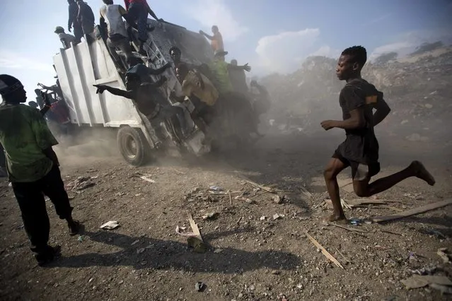 In this August 28, 2018 photo, scavengers climb on a trash truck arriving to unload at the Truitier landfill in the Cite Soleil slum of Port-au-Prince, Haiti. Here in Cite Soleil, poisonous waste decomposes into the soil, seeping into nearby water sources and exacerbating dismal sanitary conditions. (Photo by Dieu Nalio Chery/AP Photo)