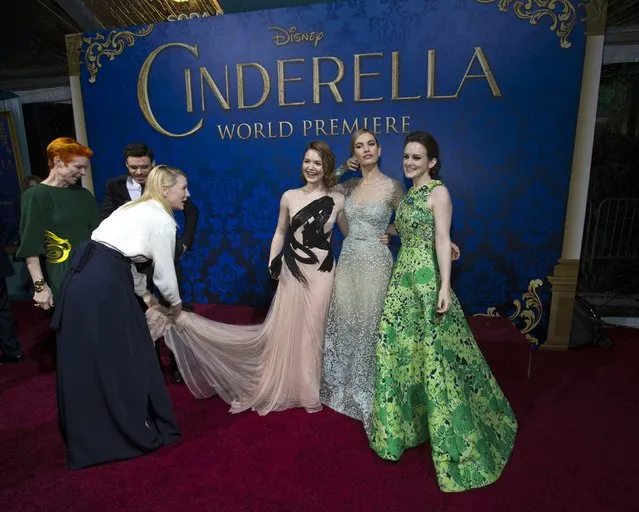 Cast members Sophie McShera (R), Lily James (2nd R) and Holliday Grainger pose, as co-star Cate Blanchett adjusts one of the gowns at the premiere of "Cinderella" at El Capitan theatre in Hollywood, California March 1, 2015. The movie opens in the U.S. on March 13. REUTERS/Mario Anzuoni  (UNITED STATES - Tags: ENTERTAINMENT)