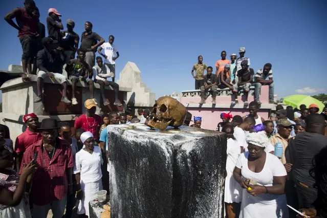 In this November 1, 2018 photo, a human skull sits on top of Baron Samedi's tomb during the annual Voodoo festival Fete Gede at Cite Soleil Cemetery in Port-au-Prince, Haiti. With the faces covered with white-powder, wearing hats and black, white and purple clothes, voodoo believers in Haiti walk through the streets and visit the cemeteries along the country during the Fete Gede, a celebration of the spirits equivalent to the Roman Catholic festivity of the Day of All Saints. (Photo by Dieu Nalio Chery/AP Photo)