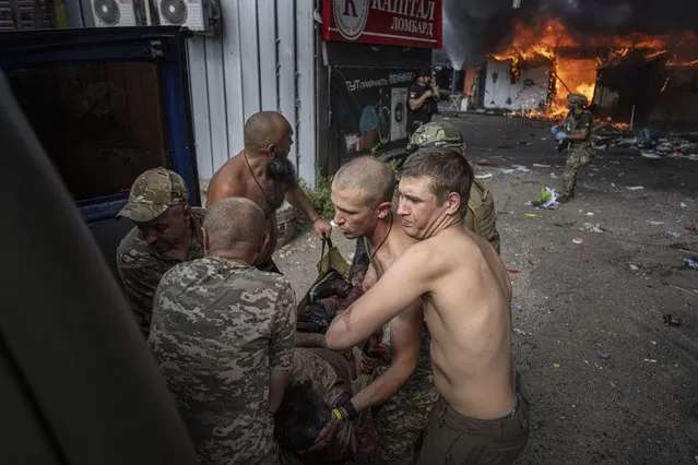 Ukrainian soldiers move to the ambulance an injured woman after a Russian rocket attack on a food market in the city center of Kostiantynivka, Ukraine, Wednesday, September 6, 2023. (Photo by Evgeniy Maloletka/AP Photo)