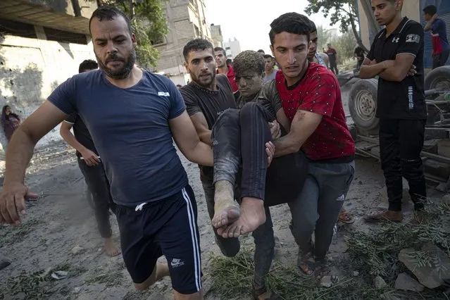 Palestinians carry a person wounded in Israeli airstrikes in Khan Younis, Gaza Strip, Monday, October 16, 2023. (Photo by Fatima Shbair/AP Photo)