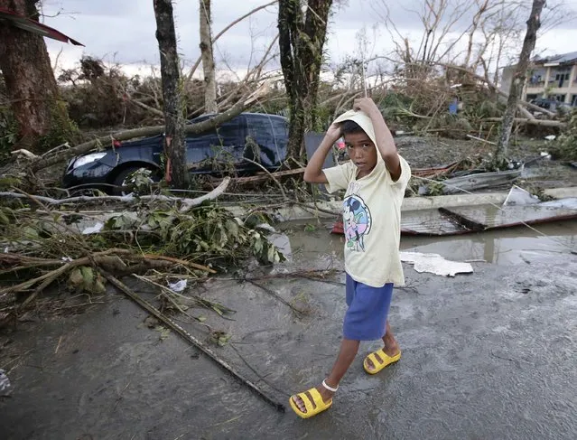A boy walks past the devastation brought about by powerful typhoon Haiyan at Tacloban city, in Leyte province in central Philippines Saturday November 9, 2013. (Photo by Bullit Marquez/AP Photo)