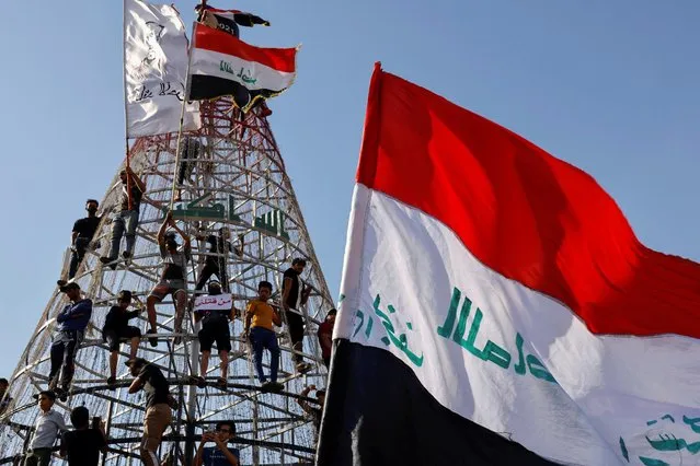 Demonstrators climb a structure during an anti-government protest in Baghdad, Iraq on May 25, 2021. (Photo by Thaier Al-Sudani/Reuters)