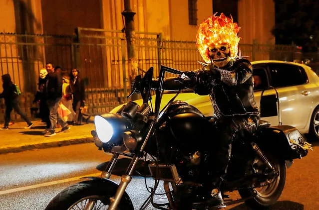 A motorcycle enthusiast celebrates Halloween wearing a mask as seen in the movie “Ghost Rider”, in Valparaiso Chile on October 31, 2023. (Photo by Rodrigo Garrido/Reuters)