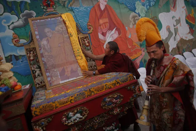 A Tibetan monk places a portrait of Tibetan spiritual leader, the Dalai Lama, on a raised platform during a special prayer ceremony on the third day of the Tibetan New Year celebrations in Kathmandu, Nepal, Thursday, February 11, 2016. (Photo by Niranjan Shrestha/AP Photo)