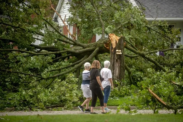 Flushing residents Donna Black, from left to right, Brenda Nyquist and Judy Doyle looks at the damage around their neighborhood as they check in with neighbors health and well-being on Thursday, August 12, 2021 in Flushing, Mich., after a wave of strong storms ravaged neighborhoods in parts of Genesee County on Wednesday night. Heavy rains are bringing flooding to parts of Michigan, as waves of thunderstorms make their way across the Midwest. (Photo by Jake May/The Flint Journal via AP Photo)