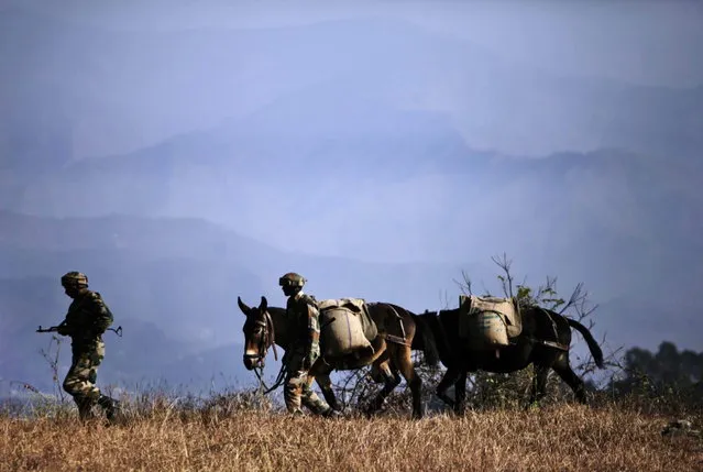 In this Monday, December 23, 2013 photo, Indian army soldiers walk with ponies carrying food supply to one of their forward posts near the Line of Control (LOC), that divides Kashmir between India and Pakistan, at Krishna Ghati (KG Sector) in Poonch, 290 kilometers (180 miles) from Jammu, India. The military commanders of longtime rivals India and Pakistan met on Tuesday in a bid to stop frequent cross-border attacks in disputed Kashmir which escalated tensions in the region in recent months. (Photo by Channi Anand/AP Photo)