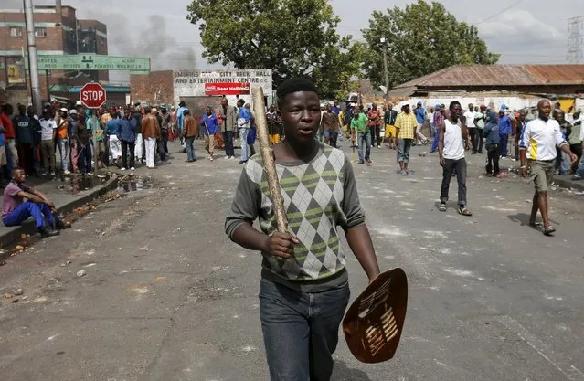 A local gestures as he holds a stick and a shield outside a hostel during anti-immigrant related violence in Johannesburg, April 17, 2015. (Photo by Siphiwe Sibeko/Reuters)
