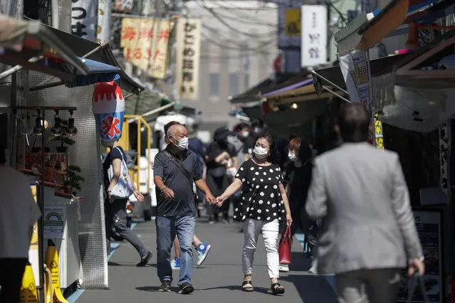 A couple wearing face masks walk through a path lined with restaurants during lunch time in Tokyo, Friday, September 10, 2021. (Photo by Hiro Komae/AP Photo)
