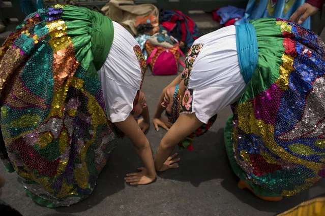 Dancers warm up in a crowded street as they prepare to perform at a gathering of supporters of a radical worker's rights organization, along Paseo de la Reforma in Mexico City, Tuesday, April 28, 2015. The “Antorchista” movement lobbies for better living conditions for workers and free housing for the poor. (Photo by Rebecca Blackwell/AP Photo)